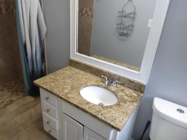 a bathroom with a granite countertop sink and a mirror