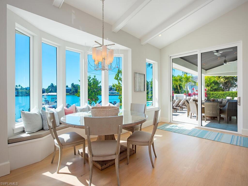 440 Springline Drive Naples, FL 34102 - Photo 13 of 28 a dining room with furniture large windows and a chandelier