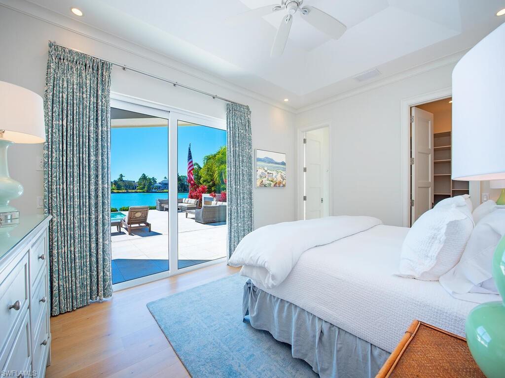 440 Springline Drive Naples, FL 34102 - Photo 20 of 28 a bedroom with a large bed and a chandelier