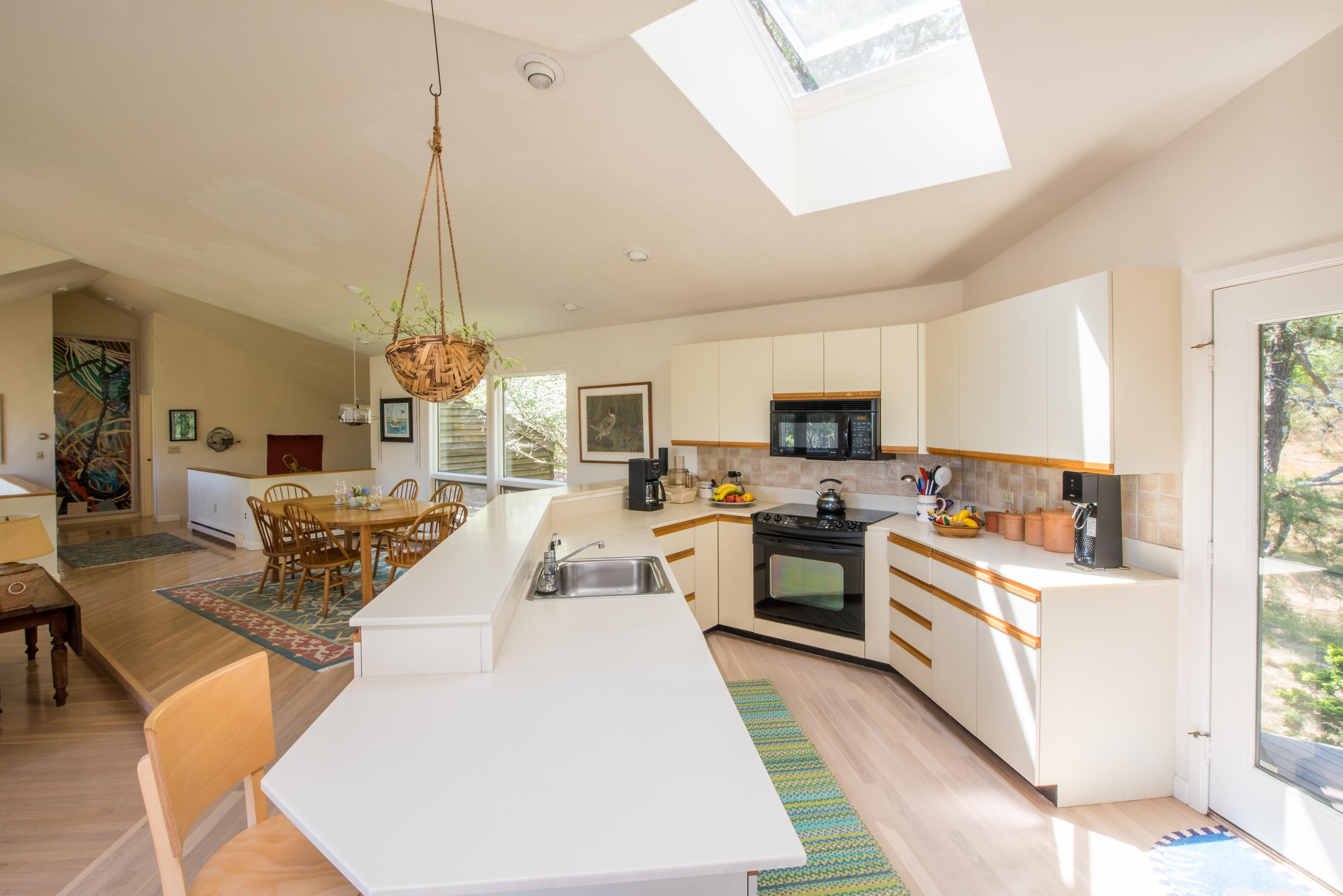 245 King Phillip Road Wellfleet, MA 02667 - Photo 6 of 33 a large kitchen with stainless steel appliances a stove a sink dishwasher a oven with a dining table and chairs with the wooden floor