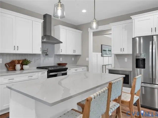 a kitchen with stainless steel appliances a sink a stove a refrigerator and white cabinets