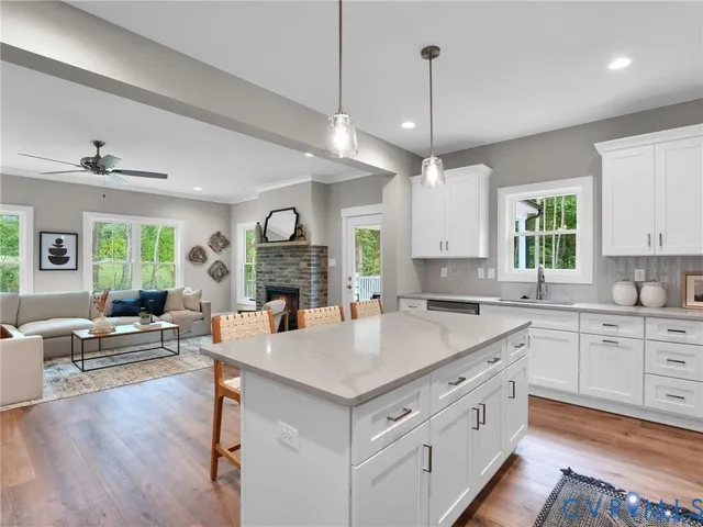 a kitchen with a stove a refrigerator a sink and couches with wooden floor