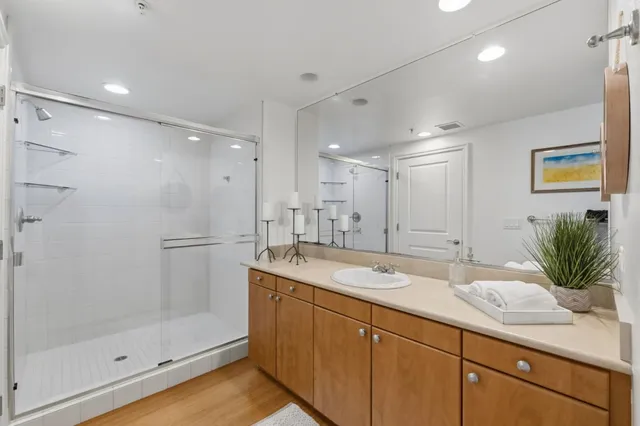 a bathroom with a granite countertop sink a mirror a glass door and shower
