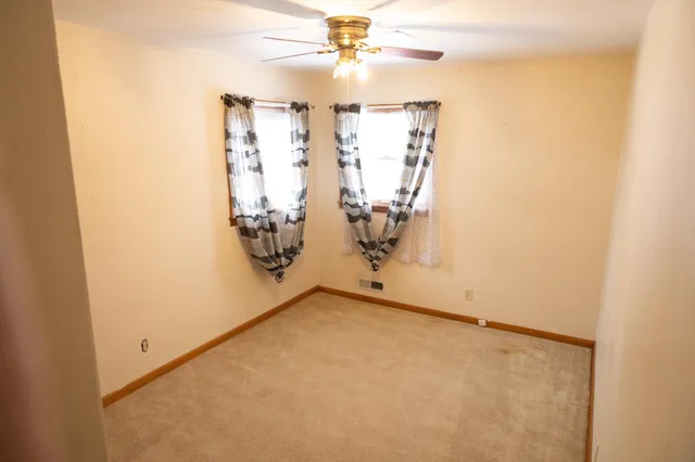 an empty room with windows and ceiling fan