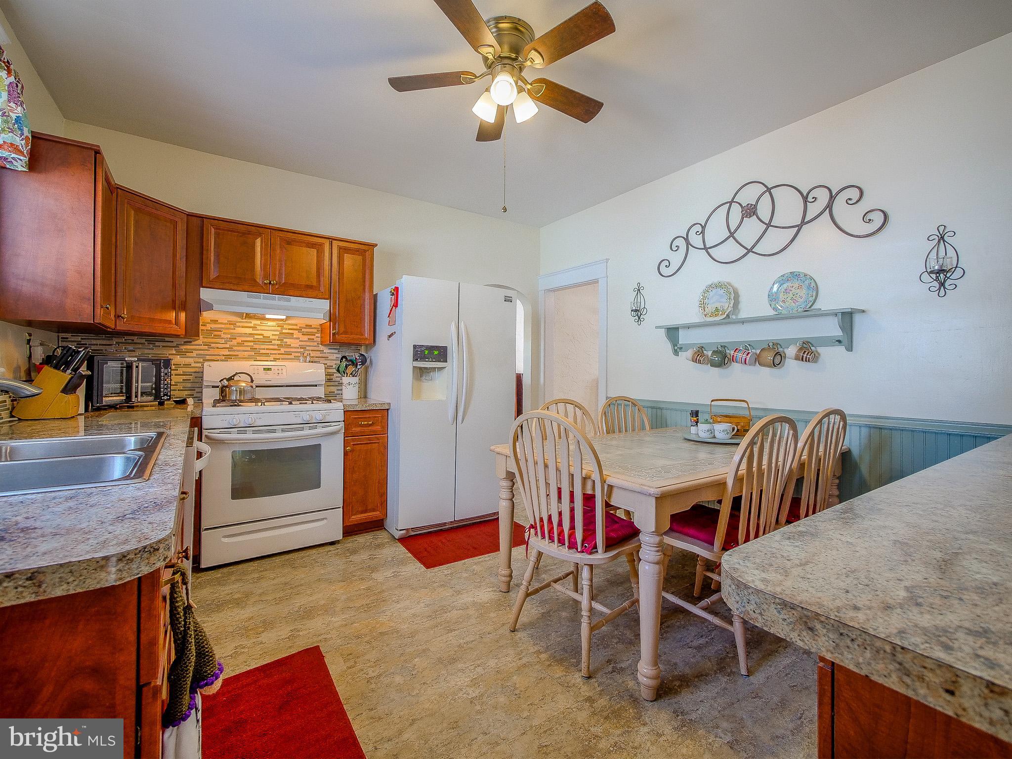 7205 Wayne Avenue Upper Darby, PA 19082 - Photo 44 of 84 a kitchen with stainless steel appliances granite countertop a stove a sink dishwasher a dining table and chairs with wooden floor