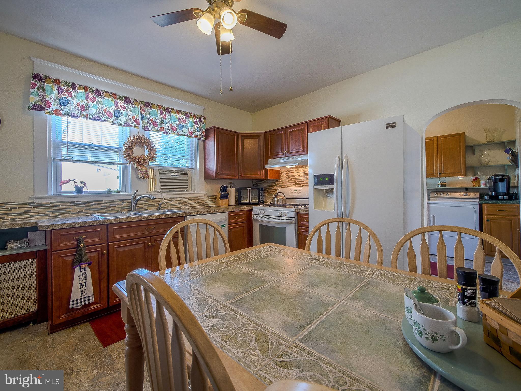 7205 Wayne Avenue Upper Darby, PA 19082 - Photo 45 of 84 a kitchen with stainless steel appliances granite countertop a stove a sink dishwasher a dining table and chairs with wooden floor