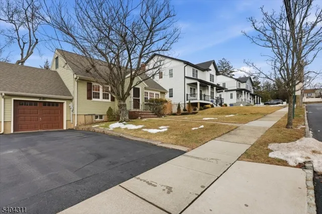 a front view of residential houses with yard and trees