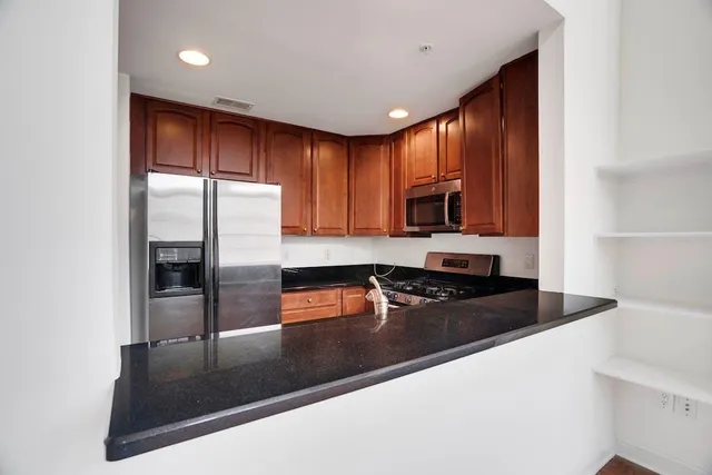 a kitchen with granite countertop a refrigerator a stove a sink and dishwasher