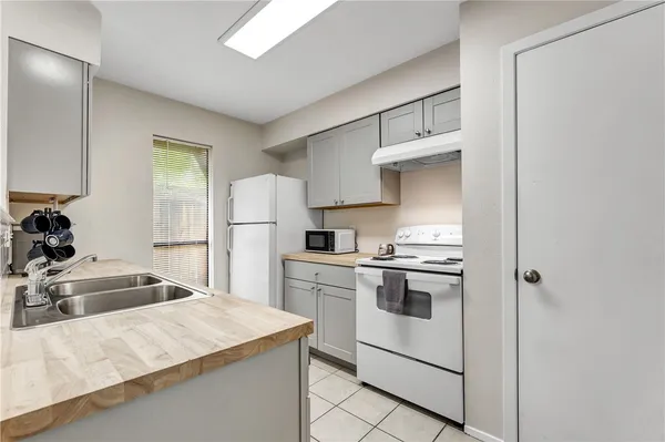 a kitchen that has a lot of white cabinets and stainless steel appliances
