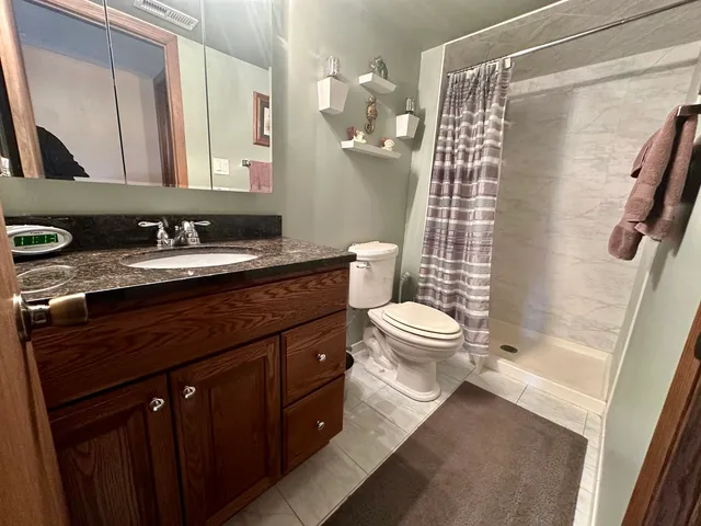 a bathroom with a granite countertop sink toilet and shower