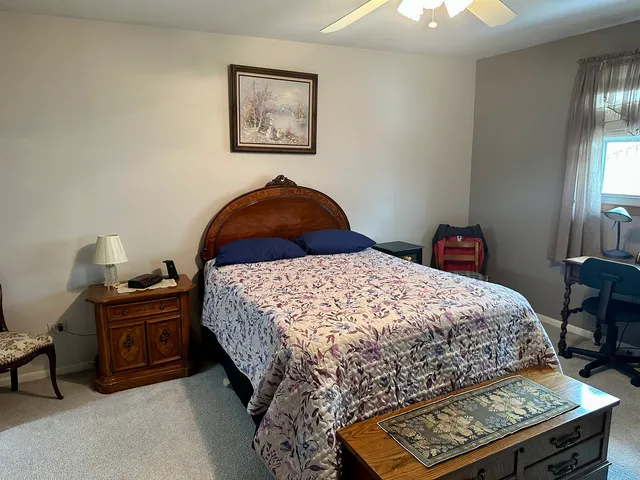 a bedroom with a bed and a lamp on dresser
