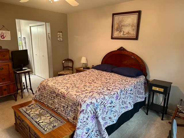 a bedroom with a bed and dresser with wooden floor