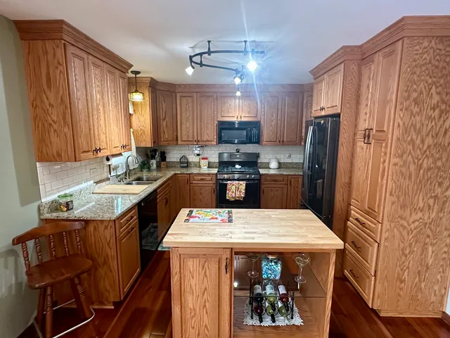 a kitchen with stainless steel appliances a sink a stove a refrigerator cabinets and a dining table