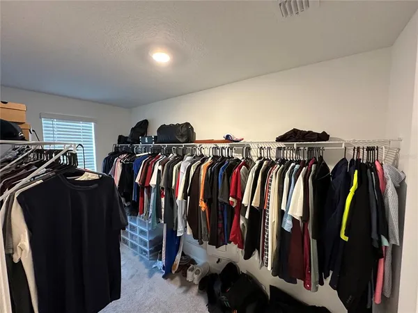 a view of walk in closet with clothes and shoes