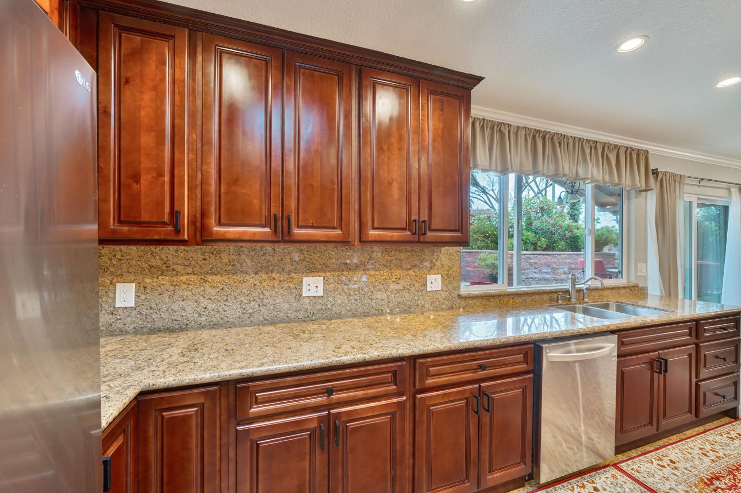 6003 Telesco Way Carmichael, CA 95608 - Photo 16 of 47 a kitchen with granite countertop wooden cabinets a sink and a window