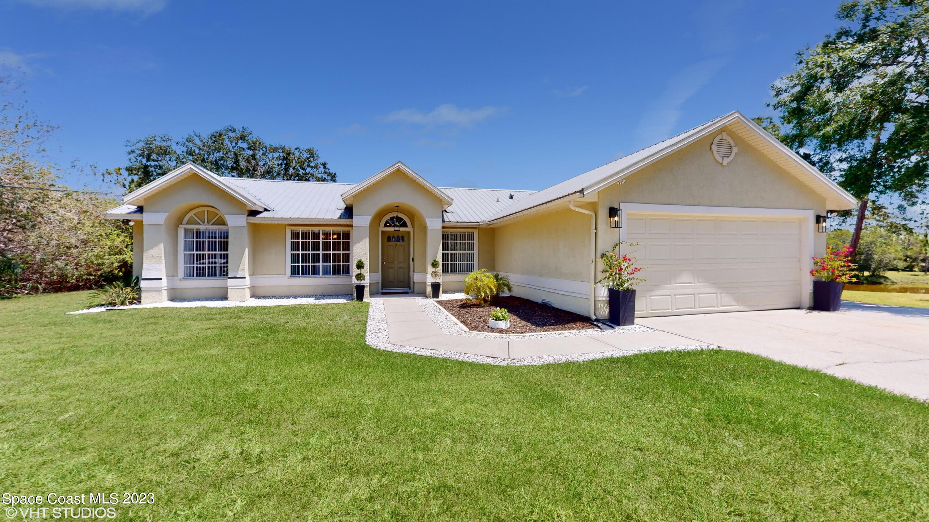 1650 Benjamin Road Malabar, FL 32950 - Photo 2 of 34 a front view of a house with a yard and garage