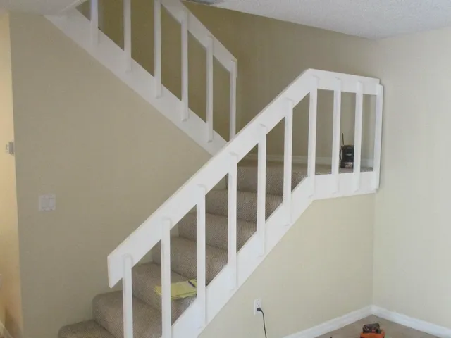 a view of staircase with railing and white walls
