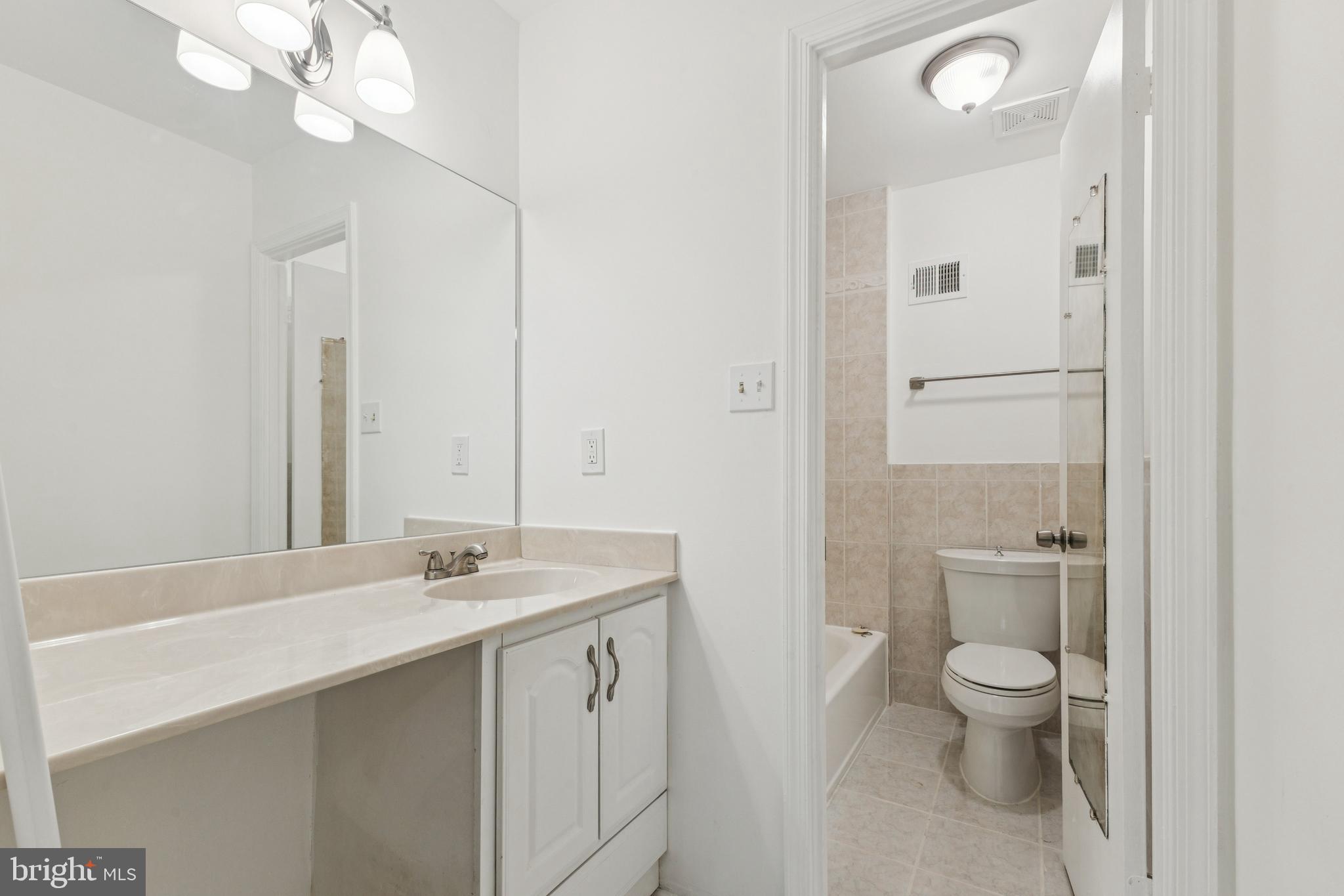 10271 Braddock Road Fairfax, VA 22032 - Photo 13 of 25 a spacious bathroom with a granite countertop sink a toilet and a mirror