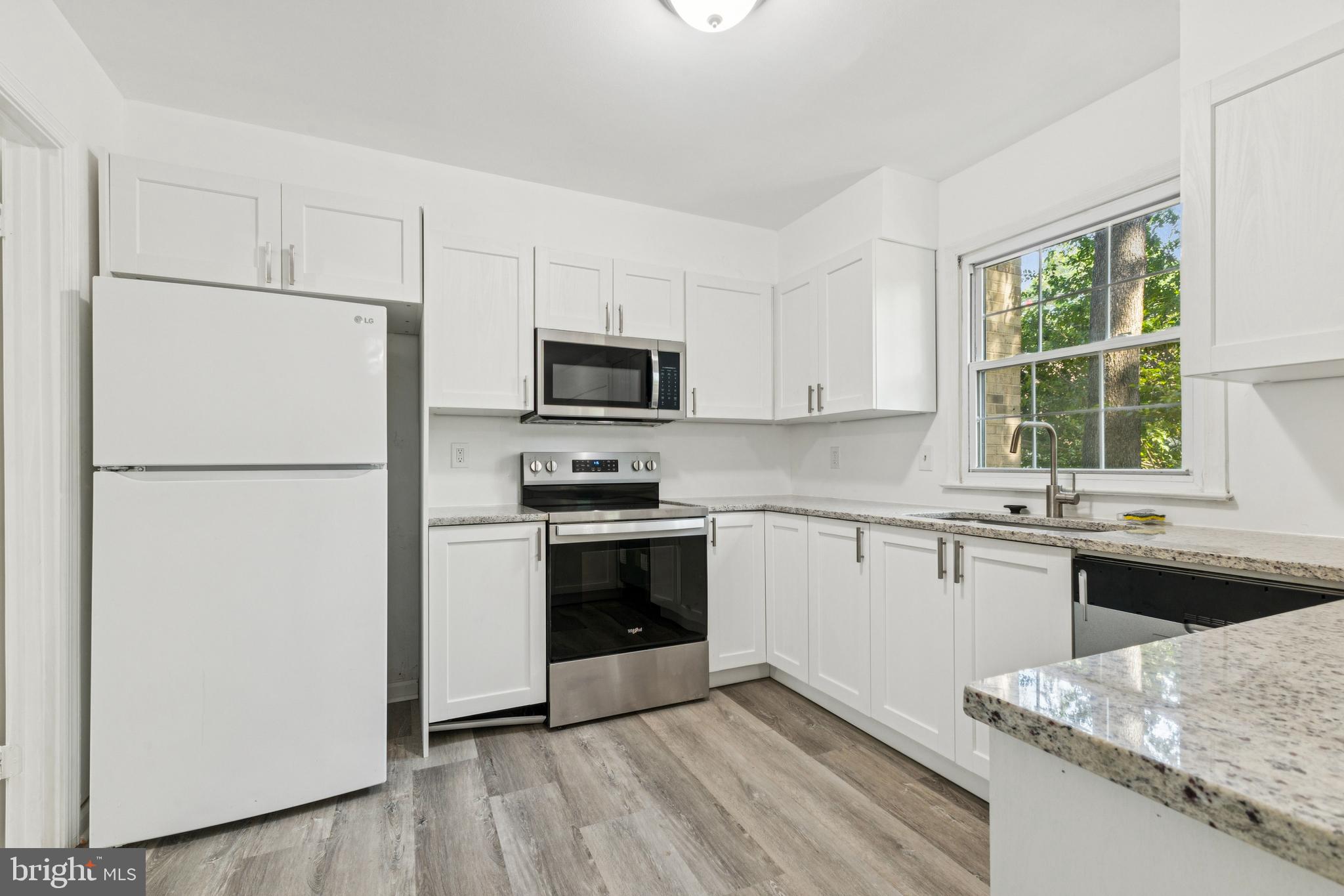 10271 Braddock Road Fairfax, VA 22032 - Photo 6 of 25 a kitchen with granite countertop a refrigerator stove a sink and dishwasher with wooden floor