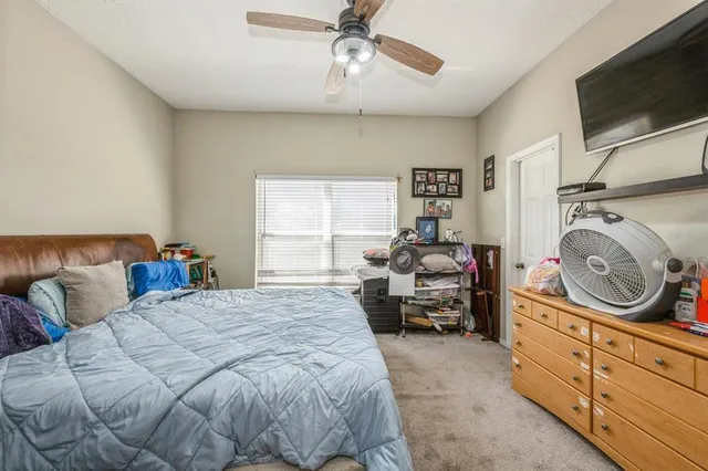 a bed room with a bed a mirror and a flat tv screen on dresser