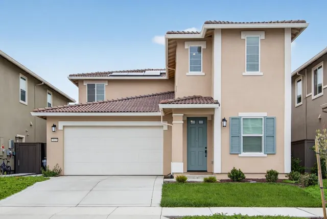 a front view of a house with a garden and garage