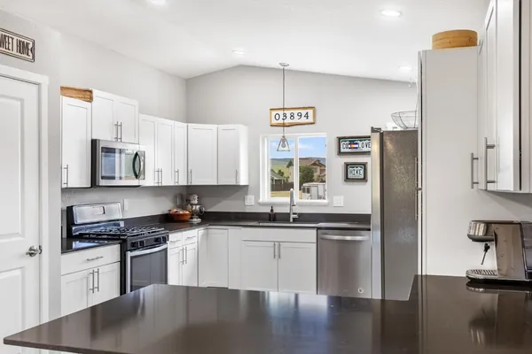 a kitchen with stainless steel appliances granite countertop a refrigerator a stove and a sink with wooden floor