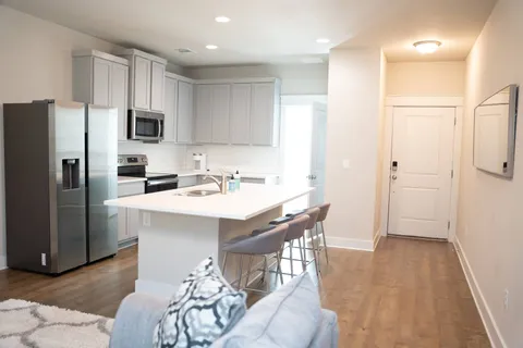a kitchen with stainless steel appliances a sink a stove a refrigerator cabinets and a dining table