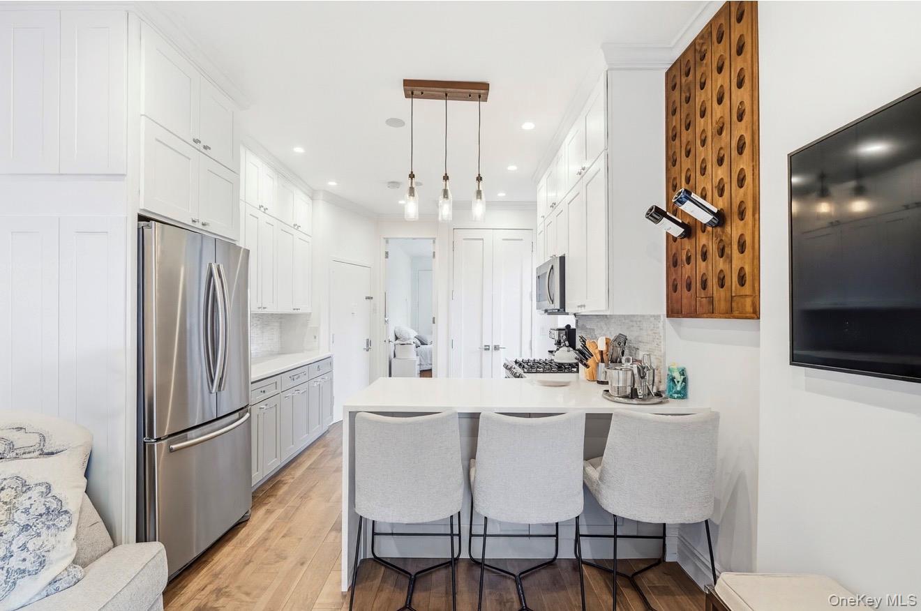 453 West 54th Street, Unit 4A Manhattan, NY 10019 - Photo 3 of 16 a kitchen with stainless steel appliances a refrigerator a sink dishwasher a dining table and chairs with wooden floor