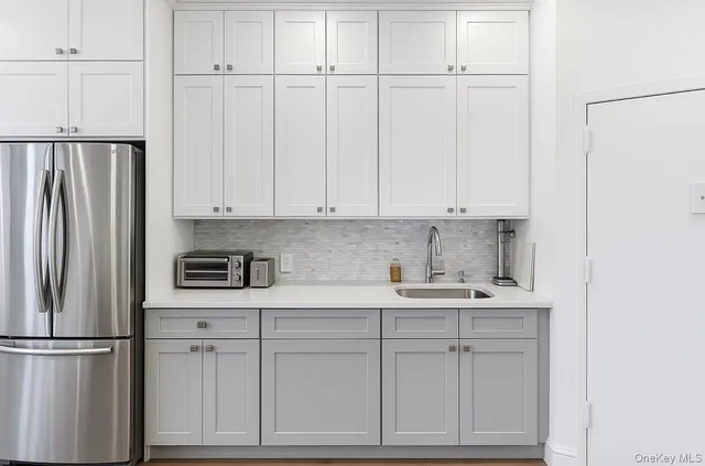 a kitchen with stainless steel appliances a refrigerator a sink dishwasher a dining table and chairs with wooden floor