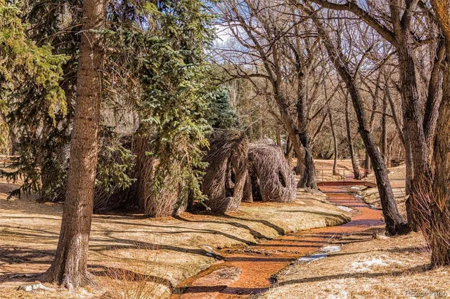 a view of a large pool with lawn chairs under an umbrella