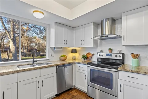 a kitchen with stainless steel appliances granite countertop a sink a stove and cabinets