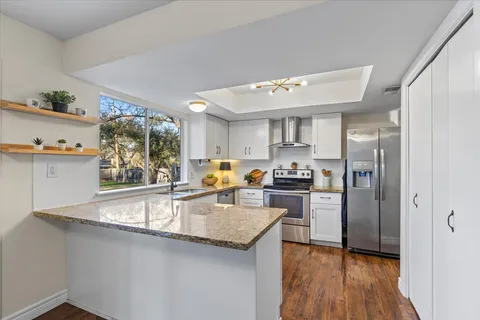 a kitchen with granite countertop stainless steel appliances a sink stove top oven and cabinets