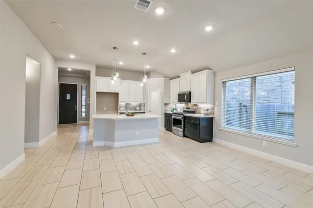 a large kitchen with stainless steel appliances granite countertop a large counter top a stove and a refrigerator