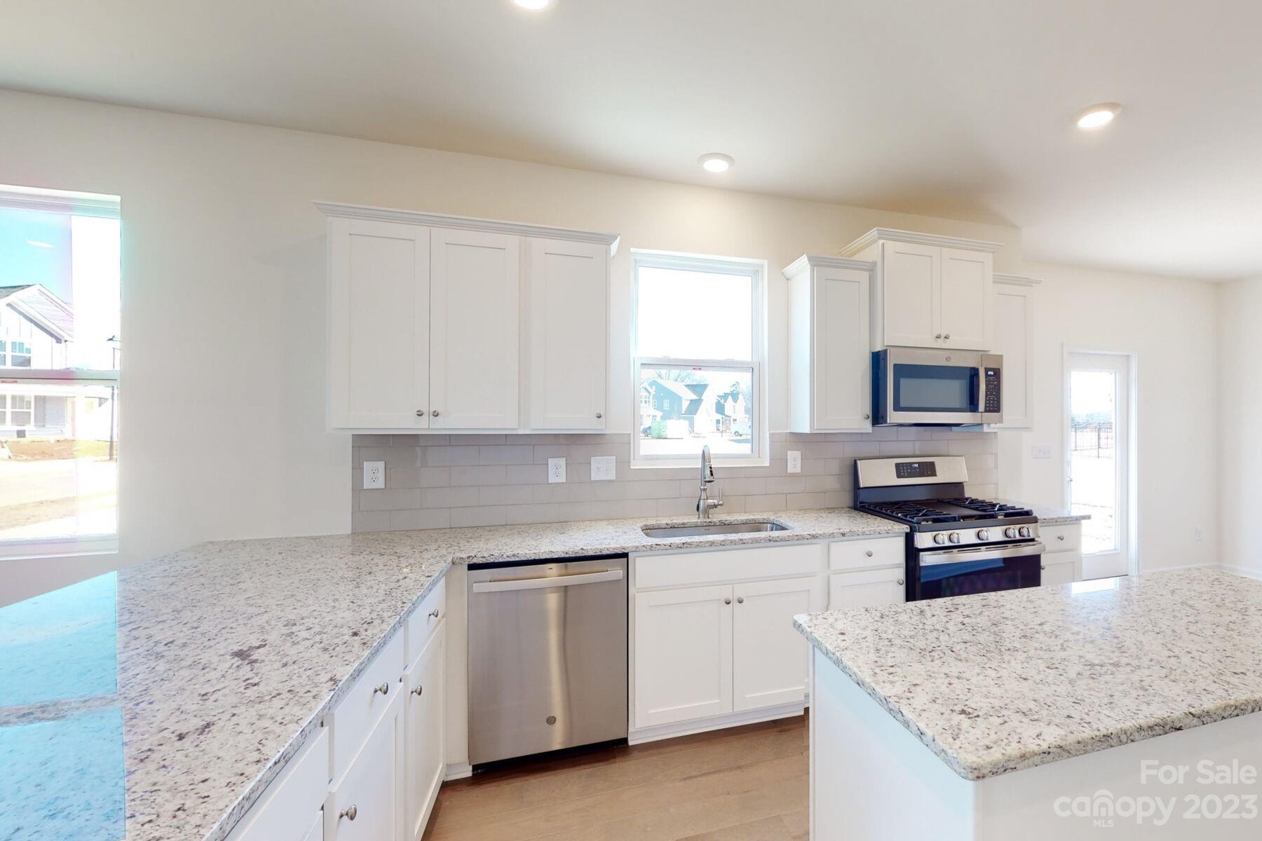 2650 Trinity Street Monroe, NC 28110 - Photo 8 of 36 a kitchen with granite countertop a sink stainless steel appliances and white cabinets