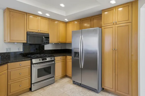 a kitchen with stainless steel appliances granite countertop a refrigerator a stove a sink and a cabinets