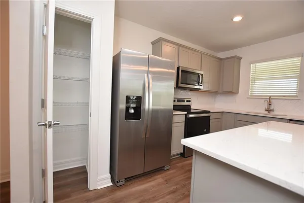 an empty room with wooden floor ceiling fan and windows