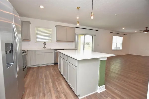 a view of an empty room with kitchen and window