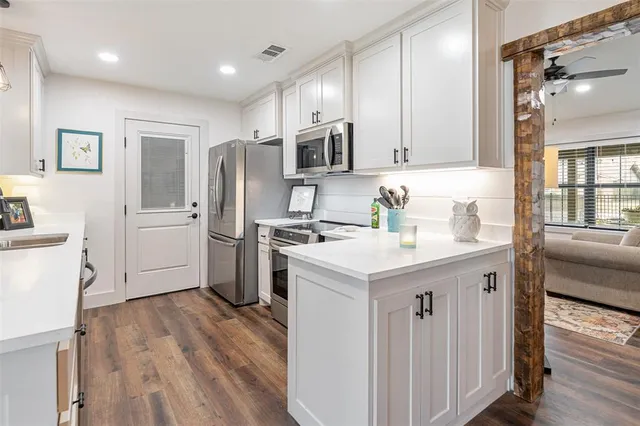 a kitchen with a sink a refrigerator a stove and white cabinets with wooden floor