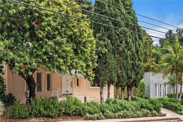 a backyard of a house with plants and large trees