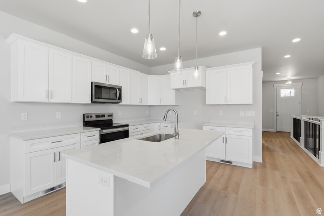 677 East 800 S Street Springville, UT 84663 - Photo 3 of 35 Kitchen featuring stainless steel appliances, white cabinets, a kitchen island with sink, light stone counters, and light wood-style floors