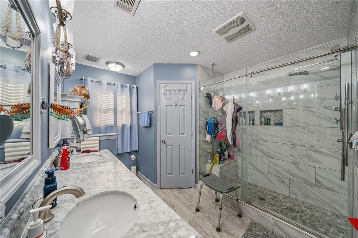 6870 Deerfield Road Bartlett, TN 38135 - Photo 13 of 28 Bathroom featuring double vanity, wood tiled floors, a shower stall, and a textured ceiling