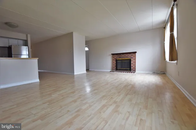 a view of an empty room with window and wooden floor