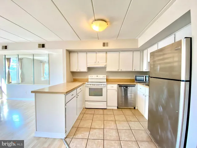 a living room with furniture kitchen view and a window