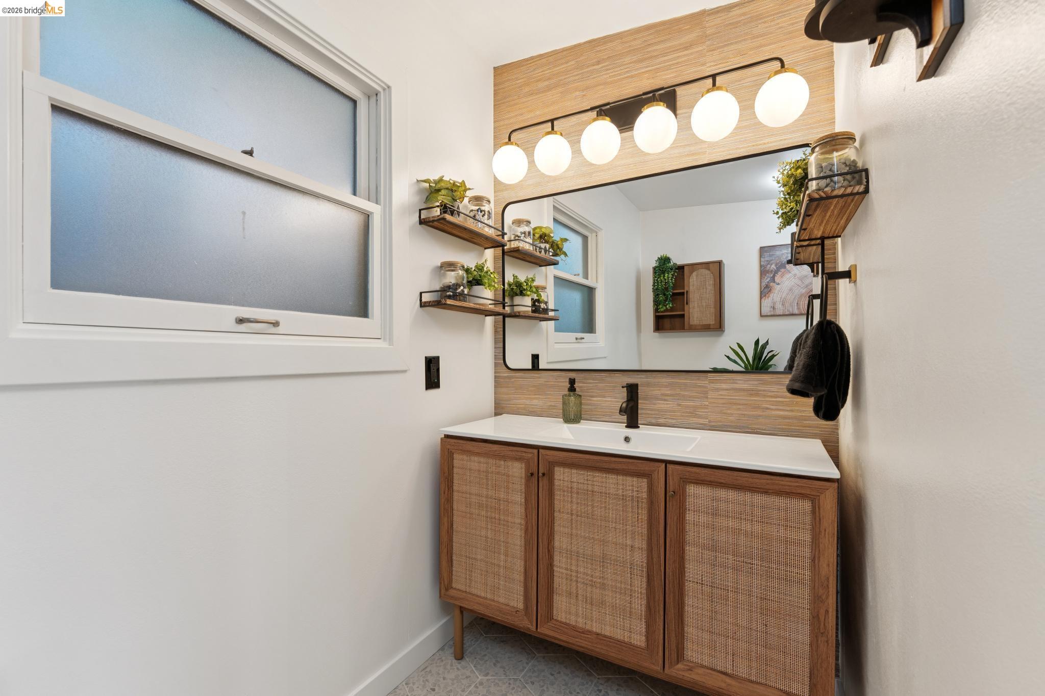 2301 Oak Street Berkeley, CA 94708 - Photo 20 of 61 Bathroom vanity featuring a white countertop with integrated sink, black wall-mounted faucet, and wood-finish cabinetry with woven inserts