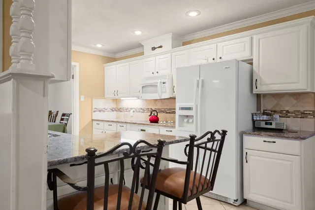 a kitchen with stainless steel appliances a refrigerator a stove a sink and white cabinets with wooden floor