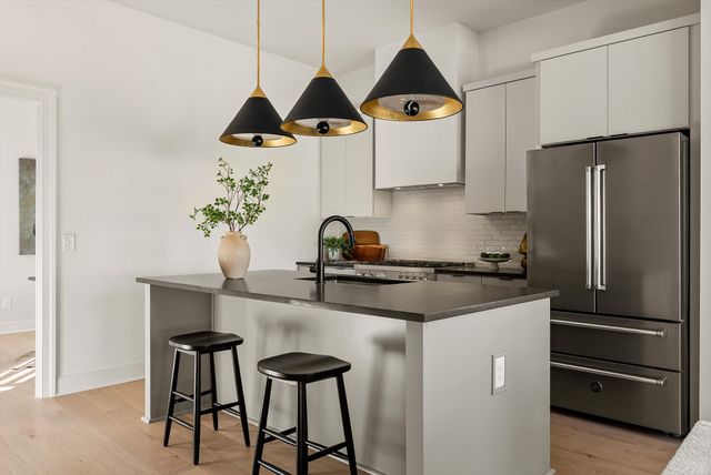 a kitchen with stainless steel appliances granite countertop a stove a sink a dining table and chairs with wooden floor