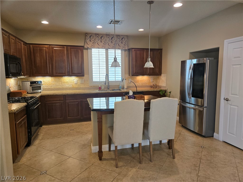 3144 Whitfeild Avenue Henderson, NV 89044 - Photo 9 of 55 A well-appointed culinary space featuring rich cabinetry and a central island with pendant lighting.