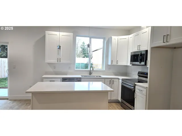 a kitchen with kitchen island granite countertop a sink cabinets and stainless steel appliances