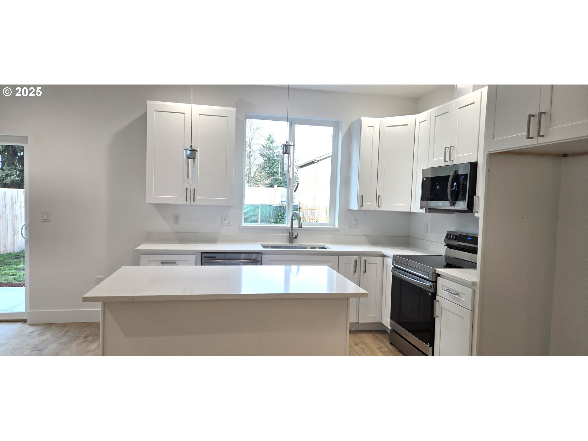 12451 Southeast Harold Street, Unit 1 Portland, OR 97236 - Photo 7 of 21 a kitchen with kitchen island granite countertop a sink cabinets and stainless steel appliances