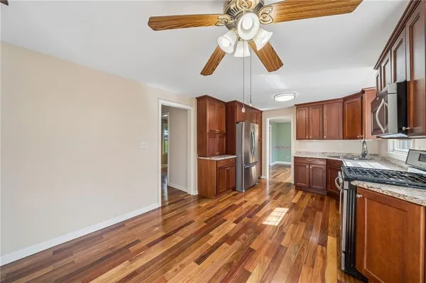 a kitchen with stainless steel appliances granite countertop a sink a stove a refrigerator cabinets and wooden floor
